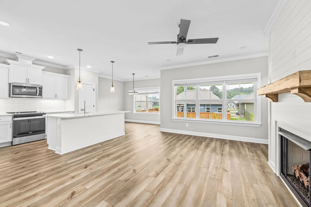 Spacious living area with hardwood floors, modern kitchen, and fireplace, crafted by Pratt Home Builders in Chattanooga TN.