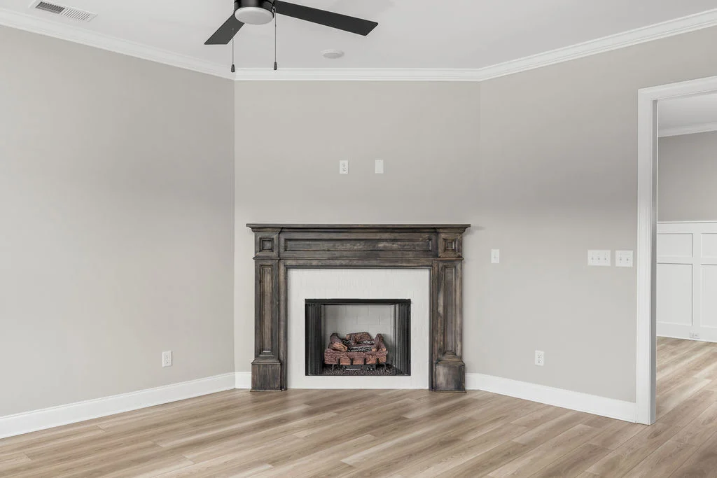 Elegant living room corner with a dark wood fireplace, light walls, and hardwood floors, designed by Pratt Home Builders in Chattanooga TN.