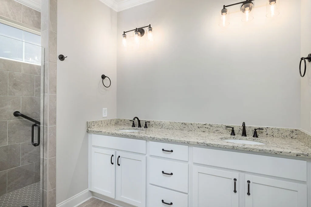 Modern bathroom with dual sinks, granite countertop, and stylish lighting, showcasing Pratt Home Builders in Chattanooga, TN.