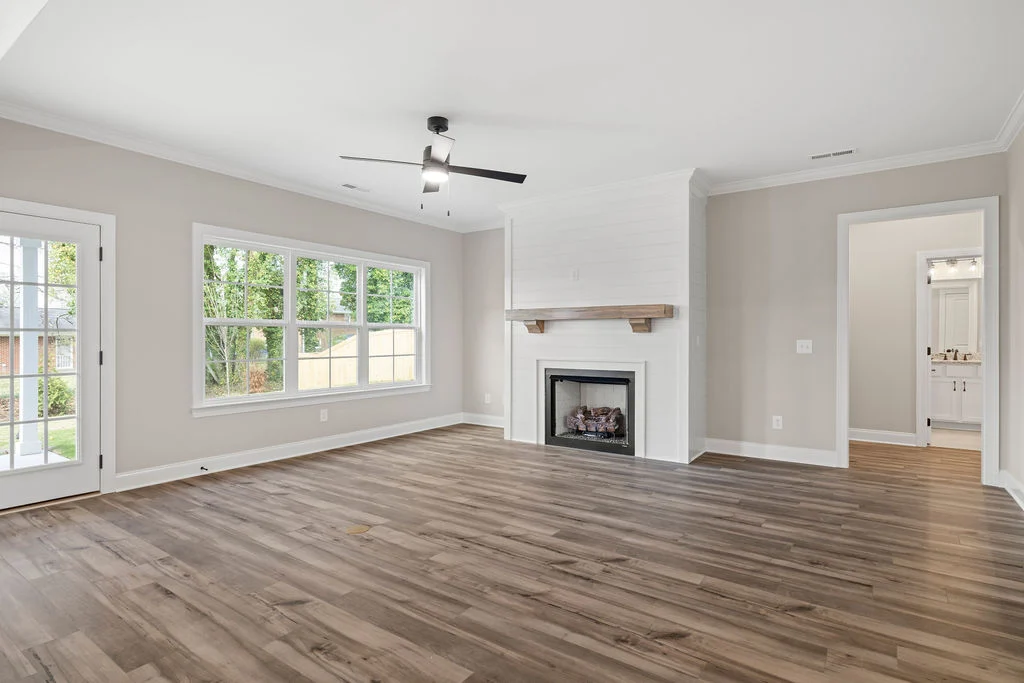 Spacious living room with hardwood floors, fireplace, large windows, and neutral tones, designed by Pratt Home Builders in Chattanooga TN.