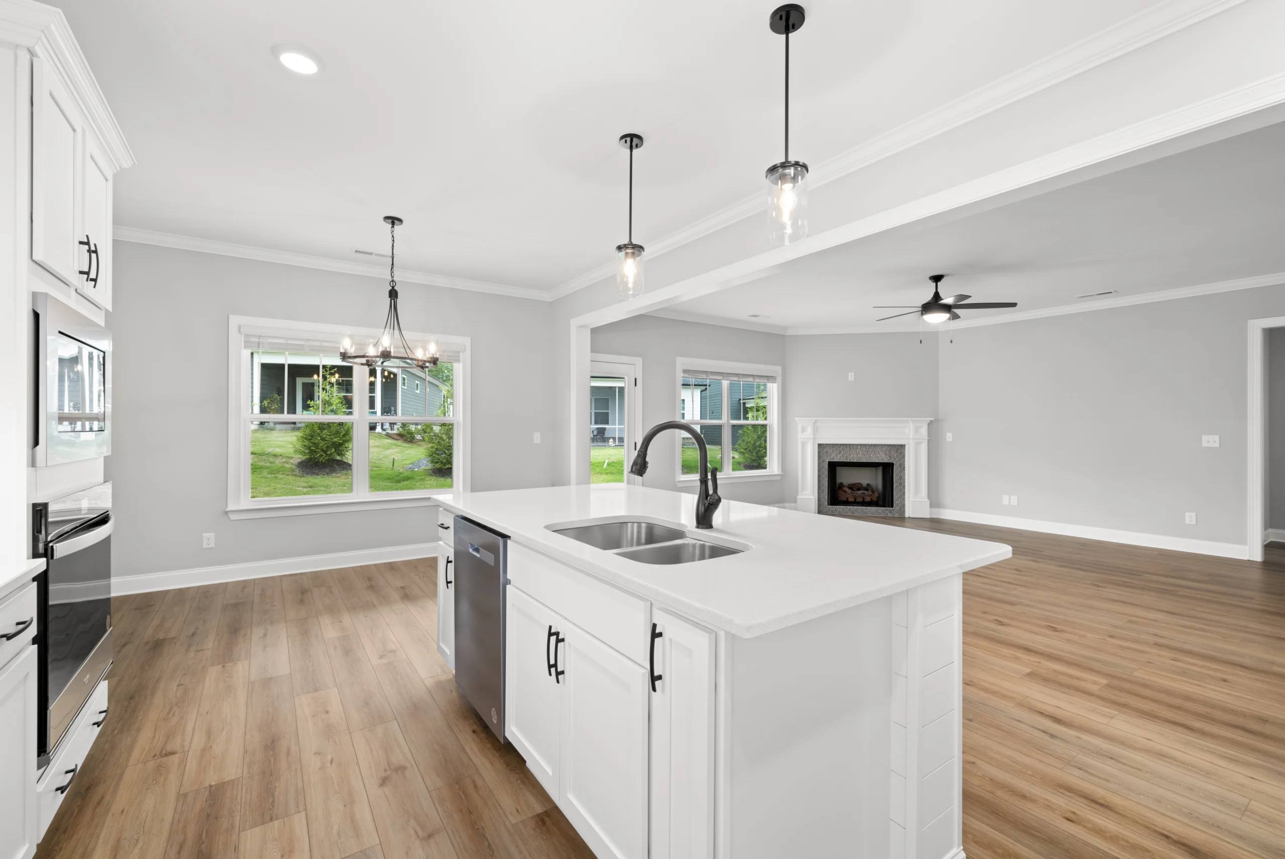 Bright open-concept kitchen and living area by Pratt Home Builders in Chattanooga TN, featuring wood floors, a modern island, and a cozy fireplace.
