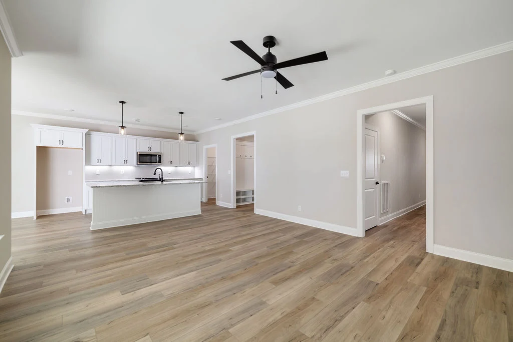 Spacious modern kitchen with white cabinets, island, and ceiling fan by Pratt Home Builders, Chattanooga TN. Light wood flooring throughout.