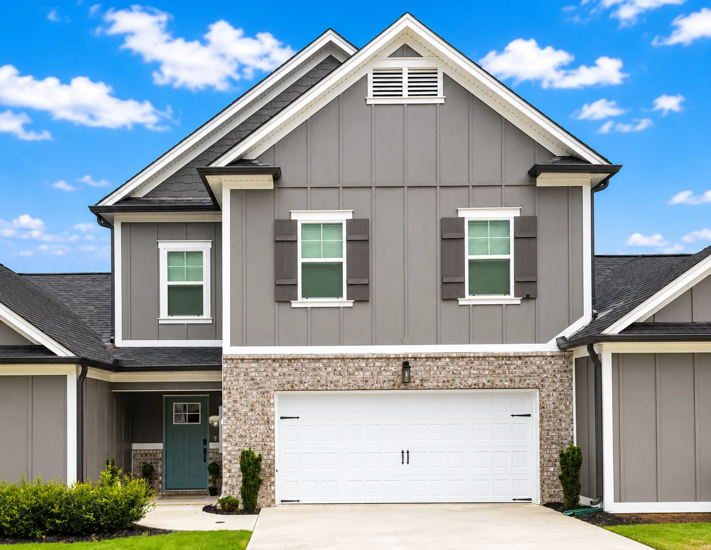 Modern gray house with brick accents, white garage door, green shutters; vibrant blue sky. Built by Pratt Home Builders in Chattanooga TN.