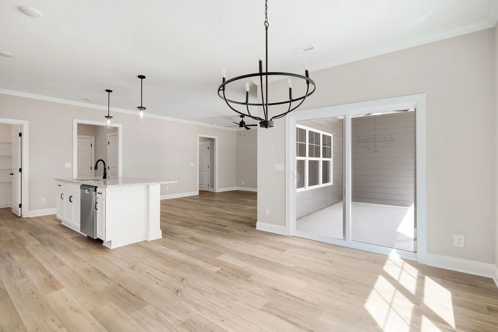 Spacious open-concept kitchen and living area by Pratt Home Builders in Chattanooga, TN, featuring hardwood floors and modern lighting fixtures.