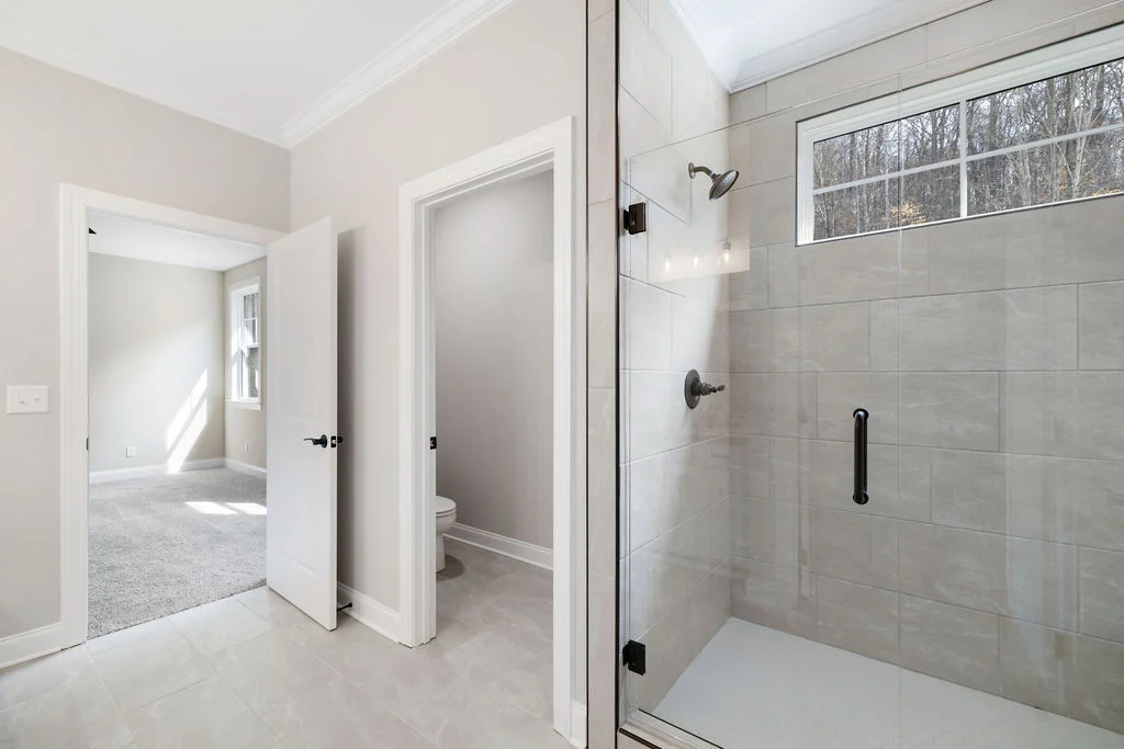 Modern bathroom by Pratt Home Builders in Chattanooga TN, featuring glass shower, adjacent room, and neutral tile flooring.