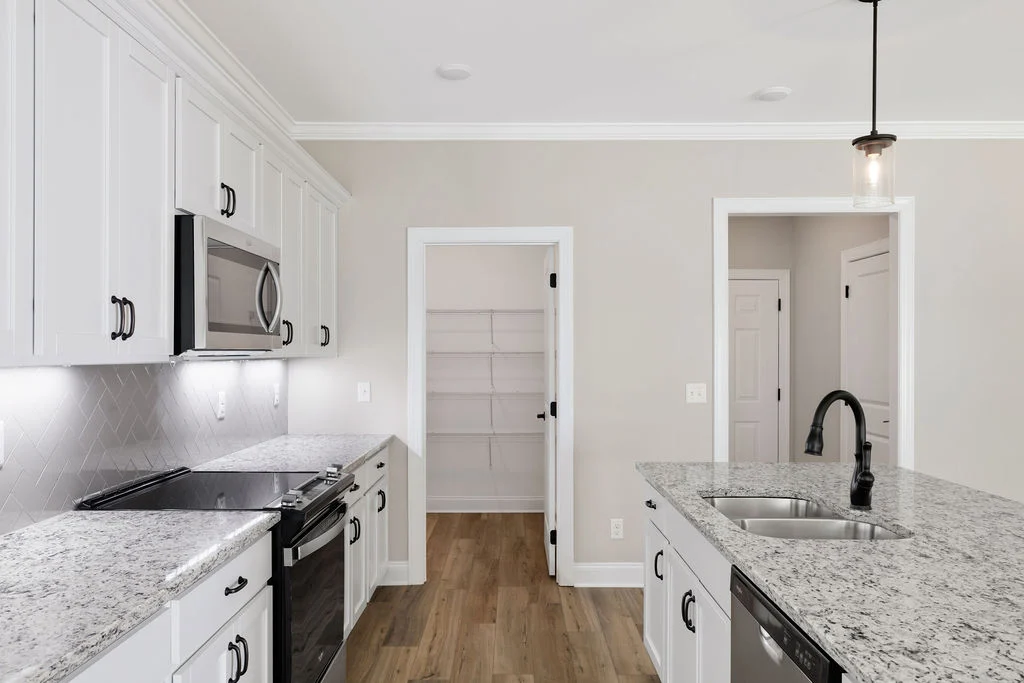 Modern kitchen with white cabinets, granite countertops, and stainless appliances. Designed by Pratt Home Builders in Chattanooga TN.
