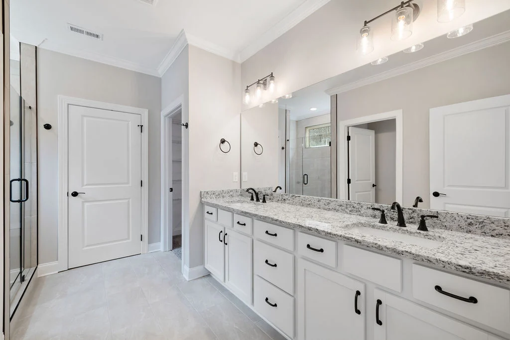 Spacious bathroom by Pratt Home Builders in Chattanooga TN, featuring double sink vanity, granite countertops, modern lighting, and glass shower.