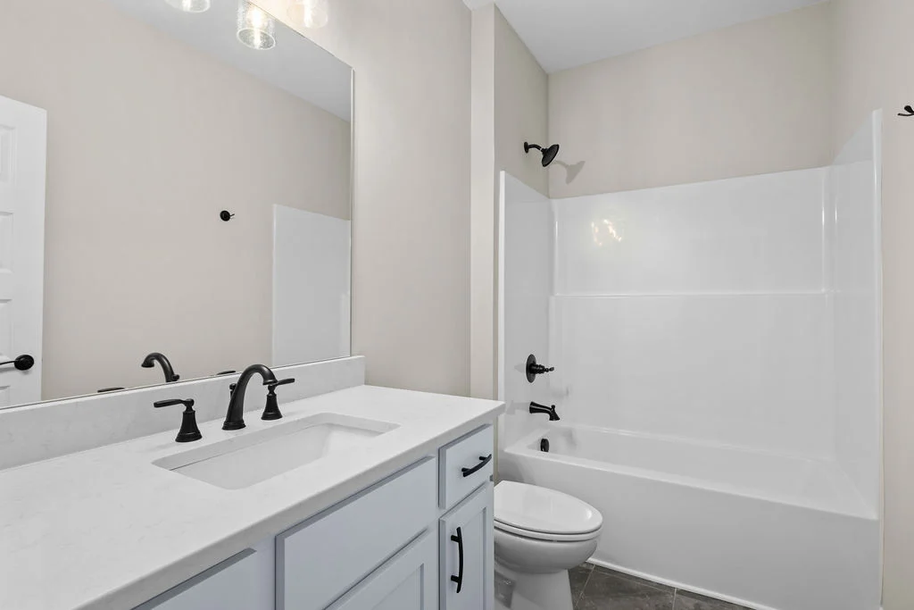 Bright bathroom with white vanity, black fixtures, and a tub-shower combo. Designed by Pratt Home Builders in Chattanooga TN.