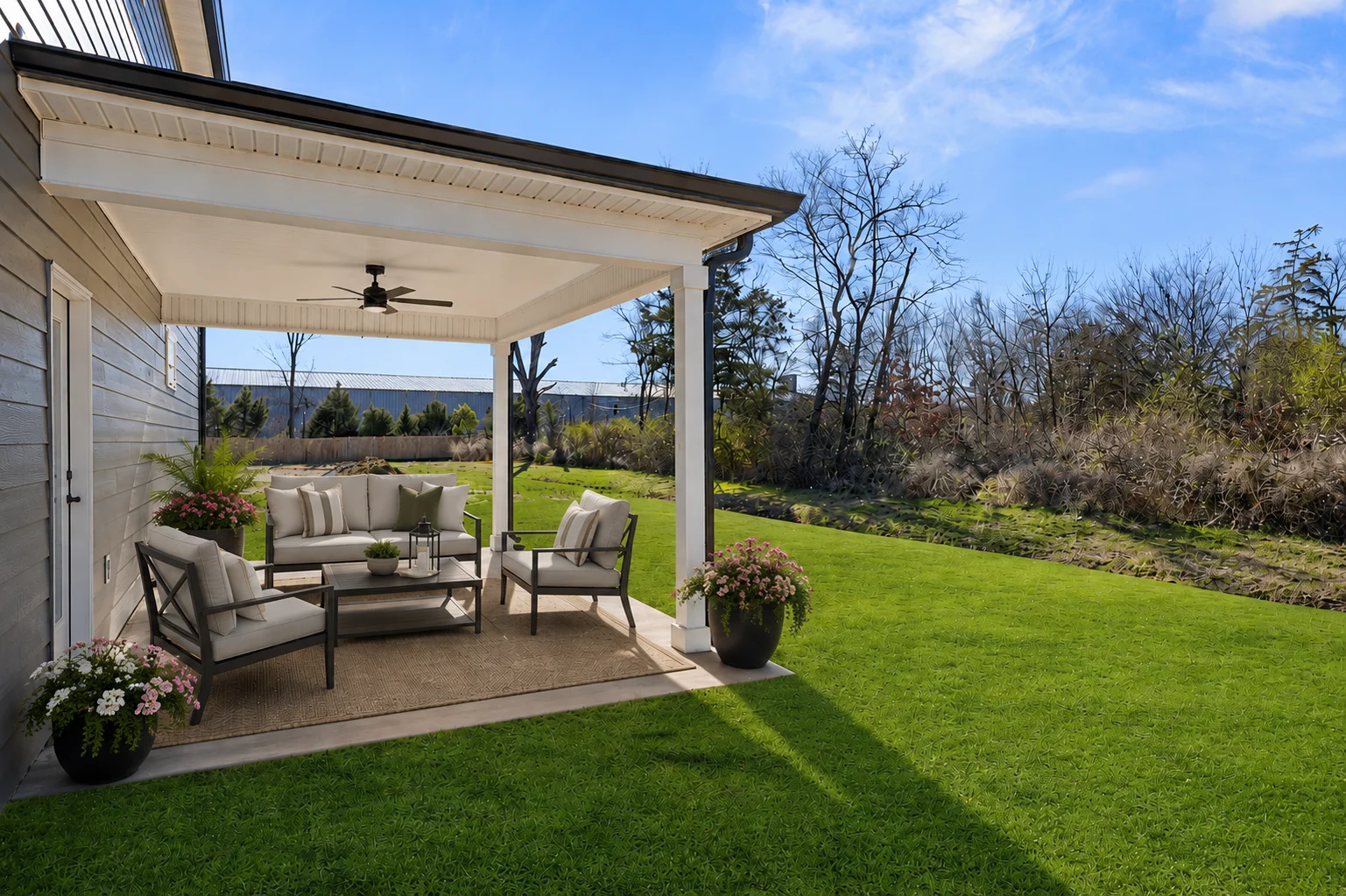 Covered patio with outdoor seating and potted plants, overlooking a lush lawn, built by Pratt Home Builders in Chattanooga TN.