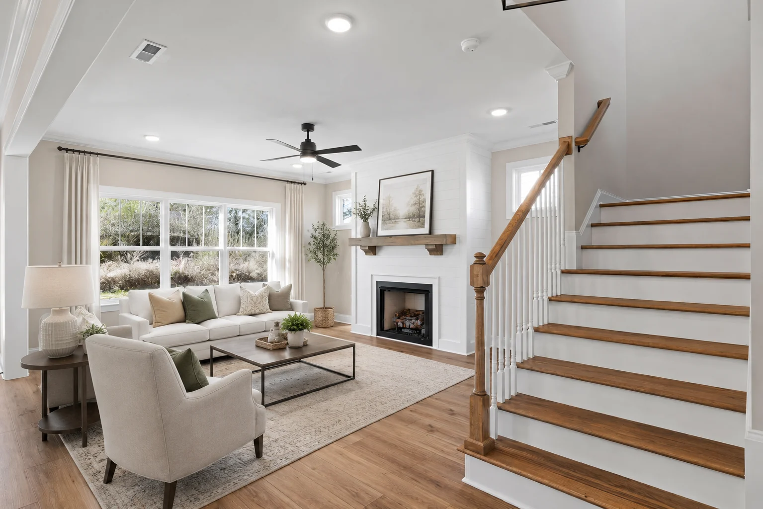 Modern living room by Pratt Home Builders in Chattanooga TN; features large windows, cozy seating, fireplace, and wooden staircase.