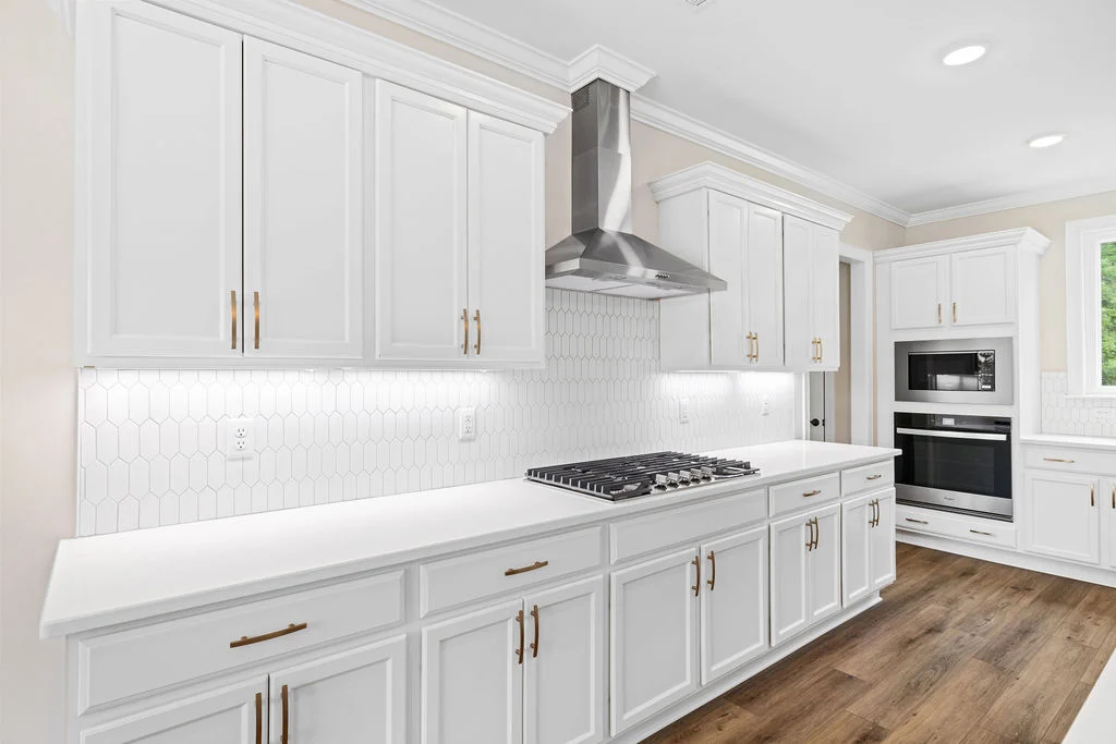 Bright kitchen with white cabinets, stainless steel appliances, and wood floor, designed by Pratt Home Builders in Chattanooga TN.