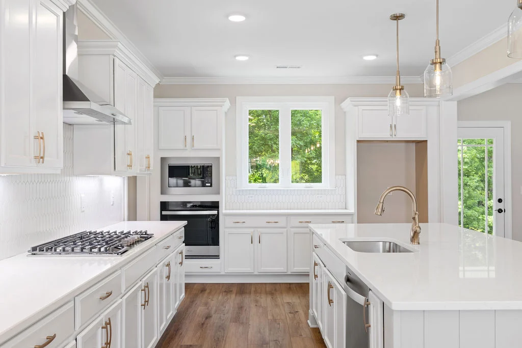 Modern kitchen with white cabinetry, large island, and stainless appliances. Designed by Pratt Home Builders in Chattanooga TN.