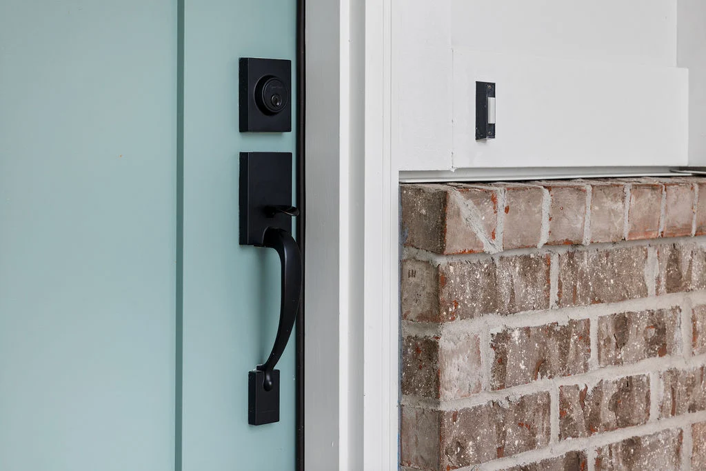 Sleek black door handle on light blue door next to a brick wall by Pratt Home Builders in Chattanooga TN.