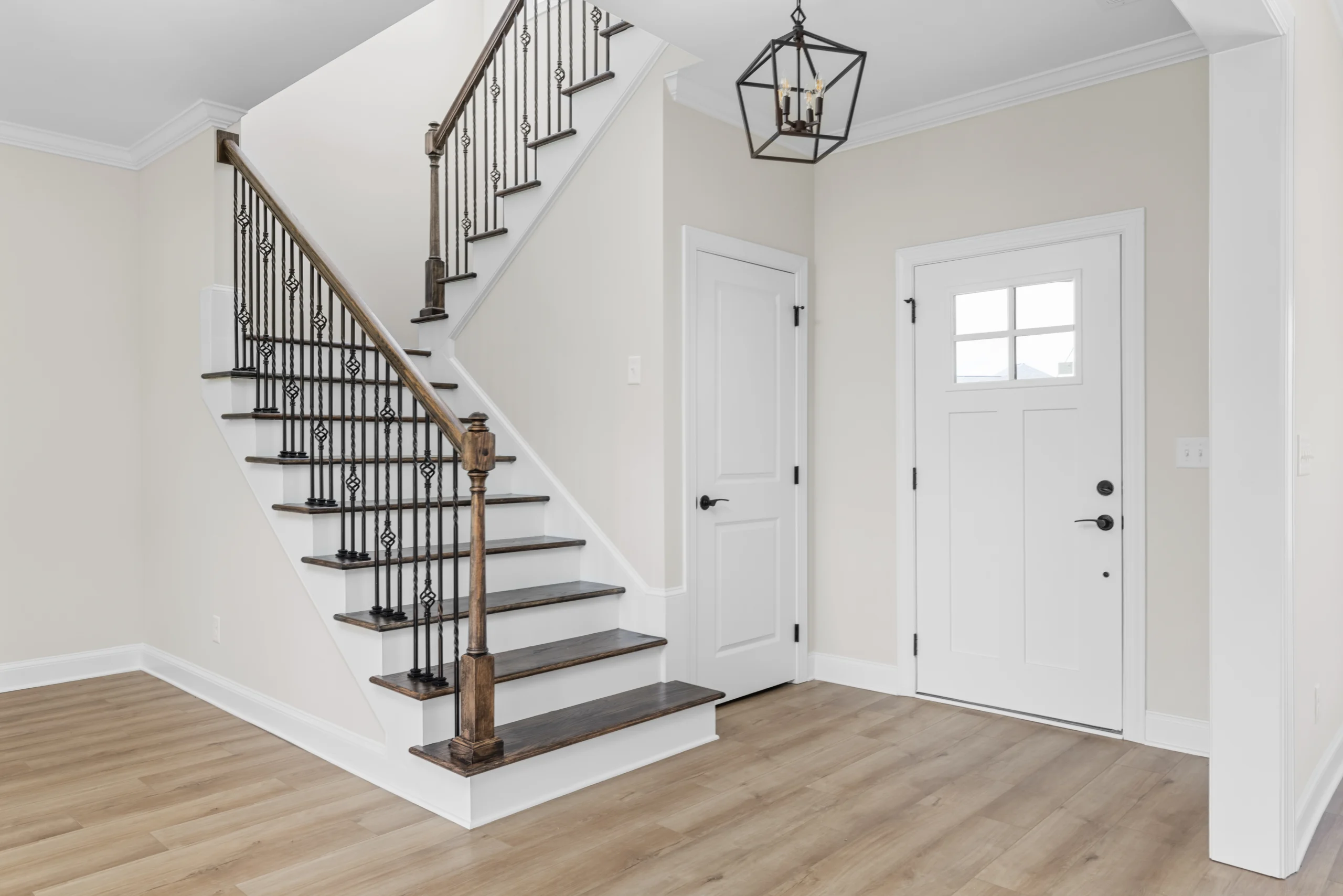 Elegant entryway with staircase featuring dark wood steps and iron railings, designed by Pratt Home Builders in Chattanooga TN.