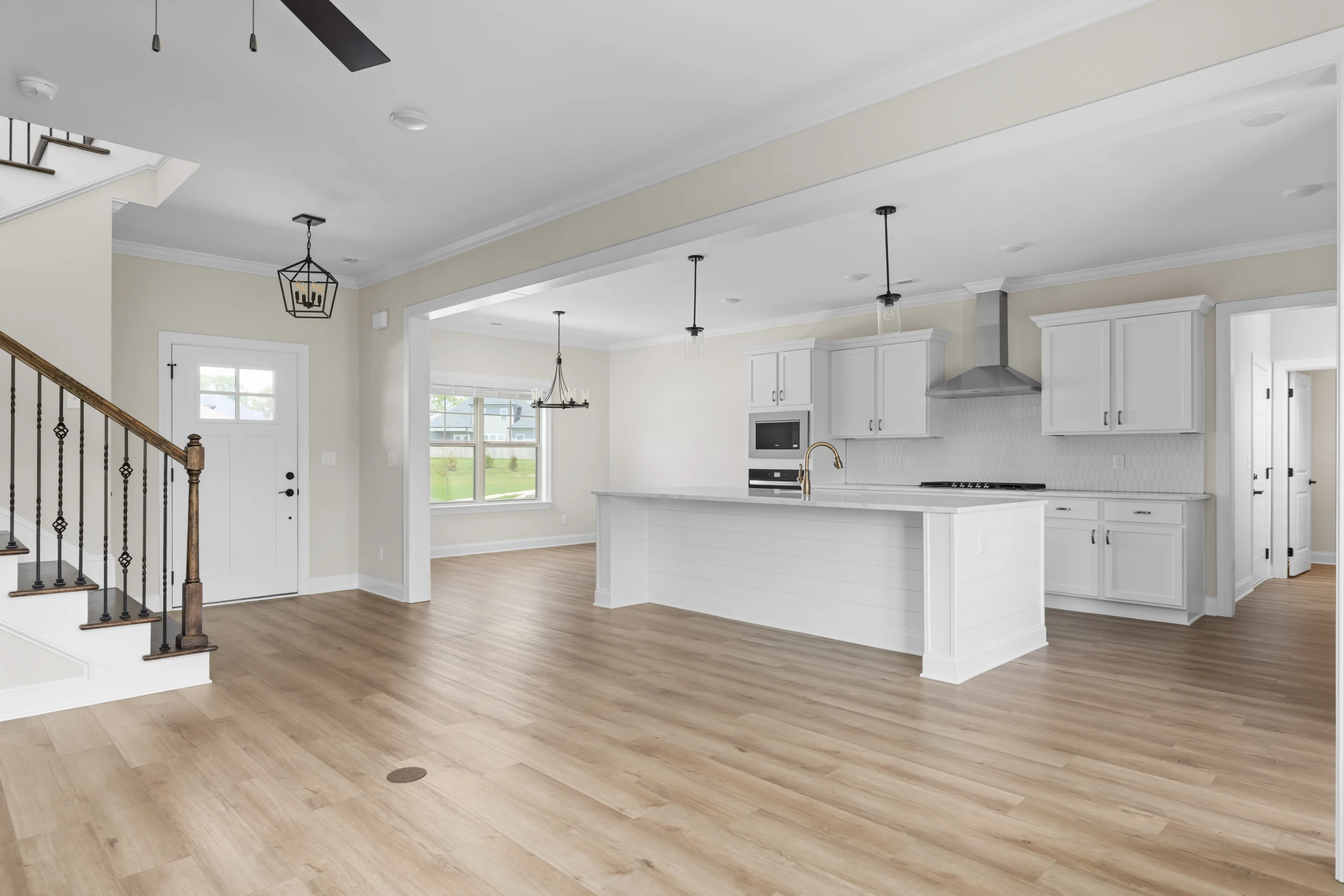 Spacious open-concept kitchen and living area by Pratt Home Builders in Chattanooga TN, featuring white cabinets and hardwood floors.