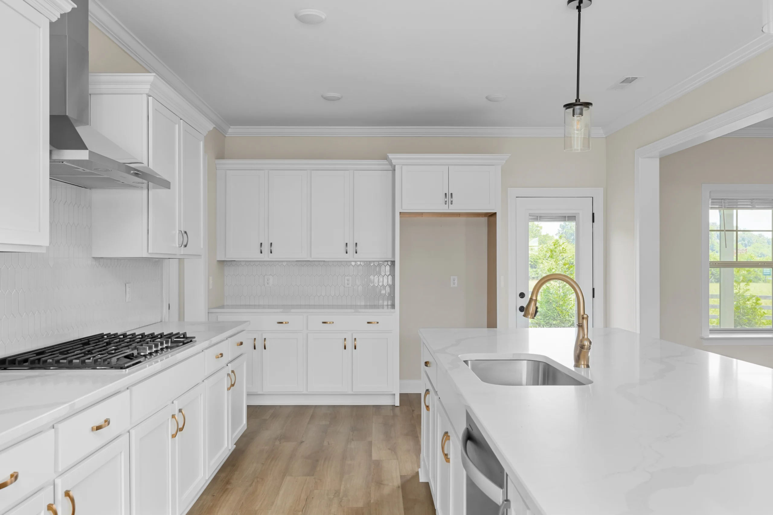 Modern kitchen with white cabinets, marble countertops, gold fixtures, hardwood floor. Designed by Pratt Home Builders in Chattanooga TN.