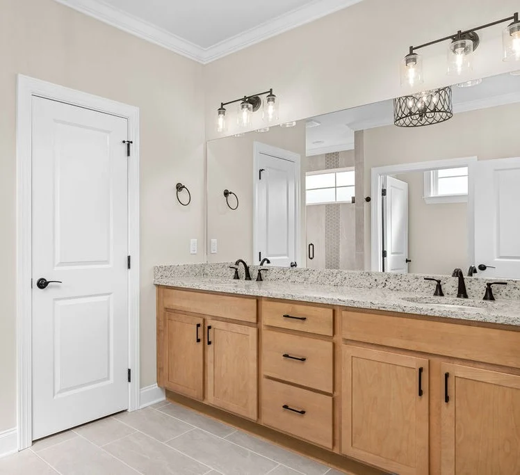 Elegant bathroom by Pratt Home Builders in Chattanooga TN, featuring a granite countertop, dual sinks, and stylish lighting fixtures.