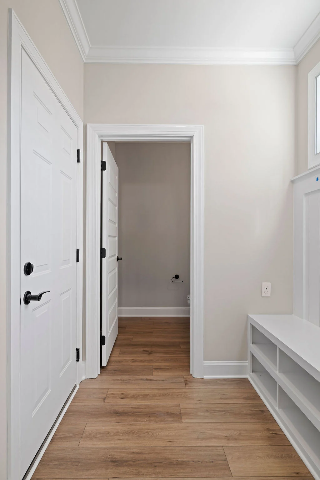 Hallway with wooden floor, white doors, and bench shelving, showcasing Pratt Home Builders' craftsmanship in Chattanooga TN.