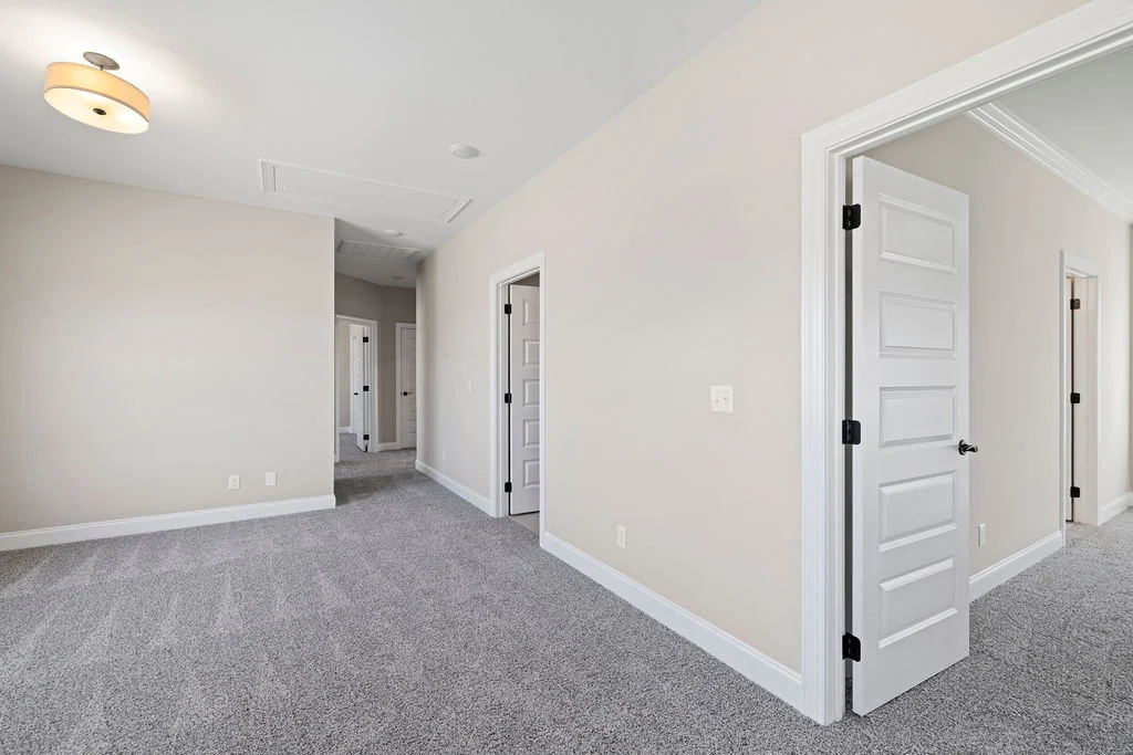 Gray-carpeted hallway with white doors and beige walls, showcasing Pratt Home Builders in Chattanooga TN design.