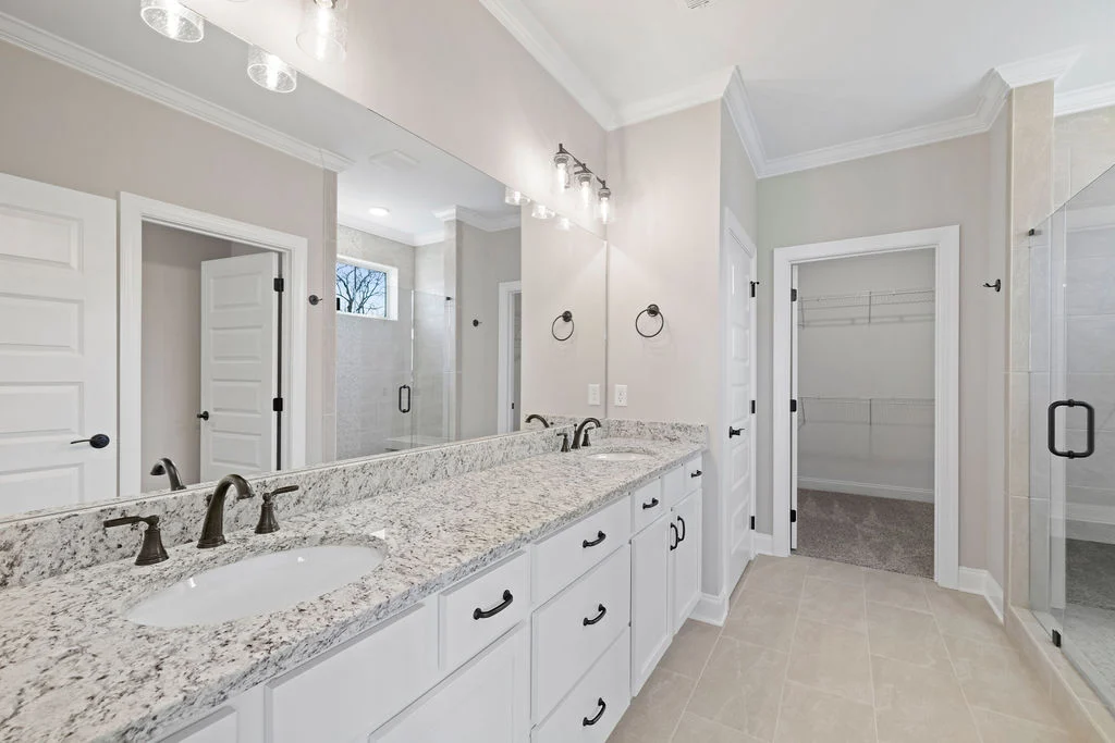 Modern bathroom with double sinks, granite countertops, spacious shower, and walk-in closet by Pratt Home Builders in Chattanooga TN.
