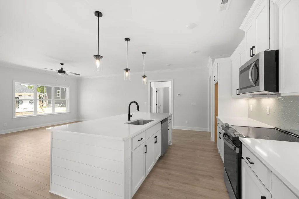 Modern kitchen with white cabinetry, island, pendant lights, and stainless appliances by Pratt Home Builders in Chattanooga TN.