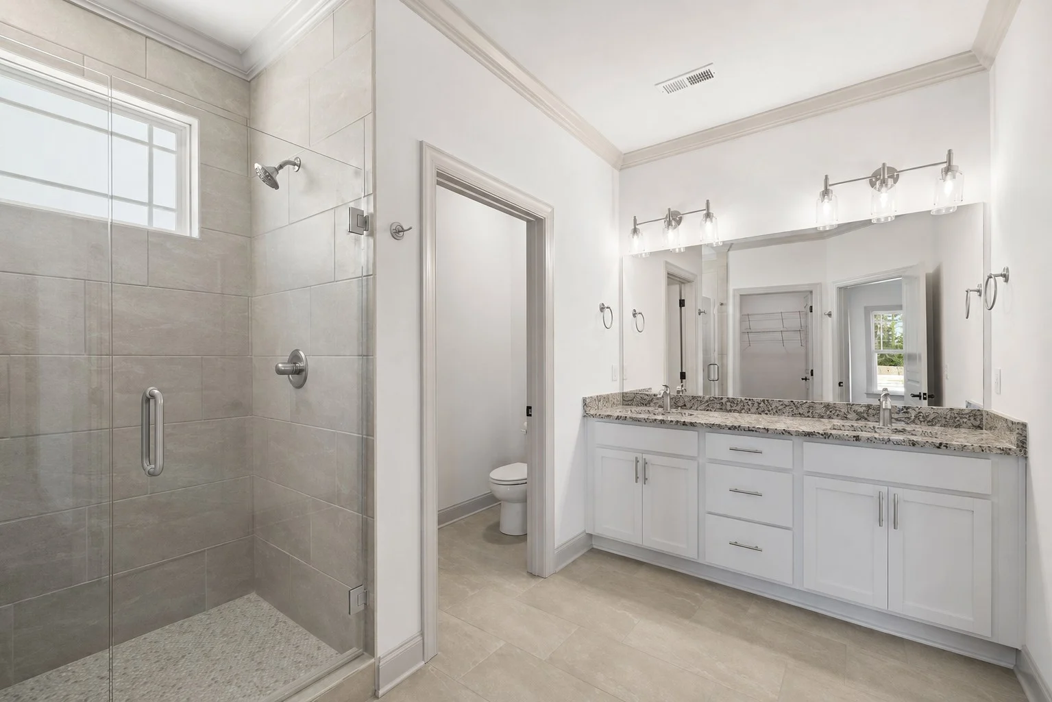Elegant bathroom by Pratt Home Builders in Chattanooga TN, featuring double sinks, granite countertop, large mirror, and a glass-enclosed shower.