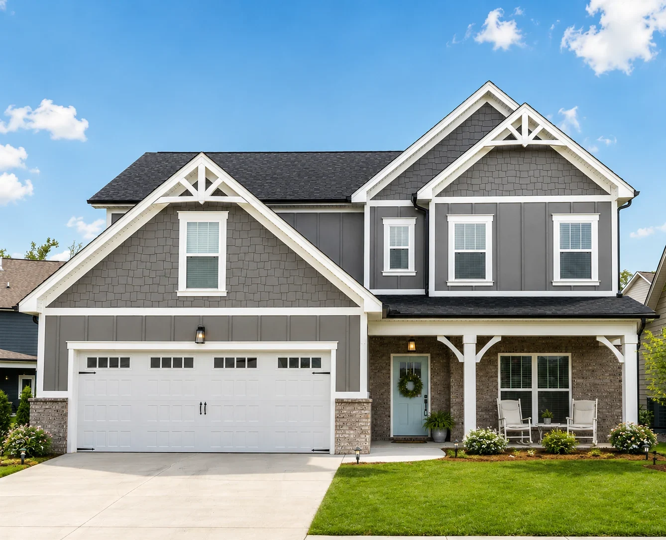 Two-story gray home with white trim, front porch, and attached garage. Built by Pratt Home Builders in Chattanooga TN, surrounded by a green lawn.