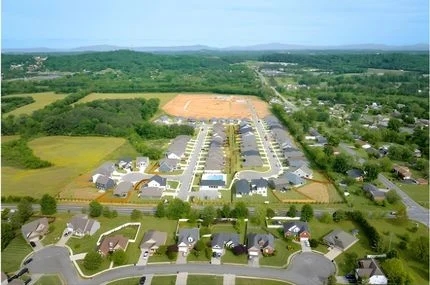 Aerial view of a developing suburban neighborhood surrounded by greenery, with new homes possibly by Pratt Home Builders in Chattanooga, TN.