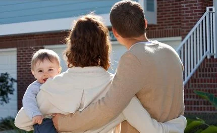 Family admiring a house, parents with child. Home features brick and light blue siding. Pratt Home Builders in Chattanooga TN.