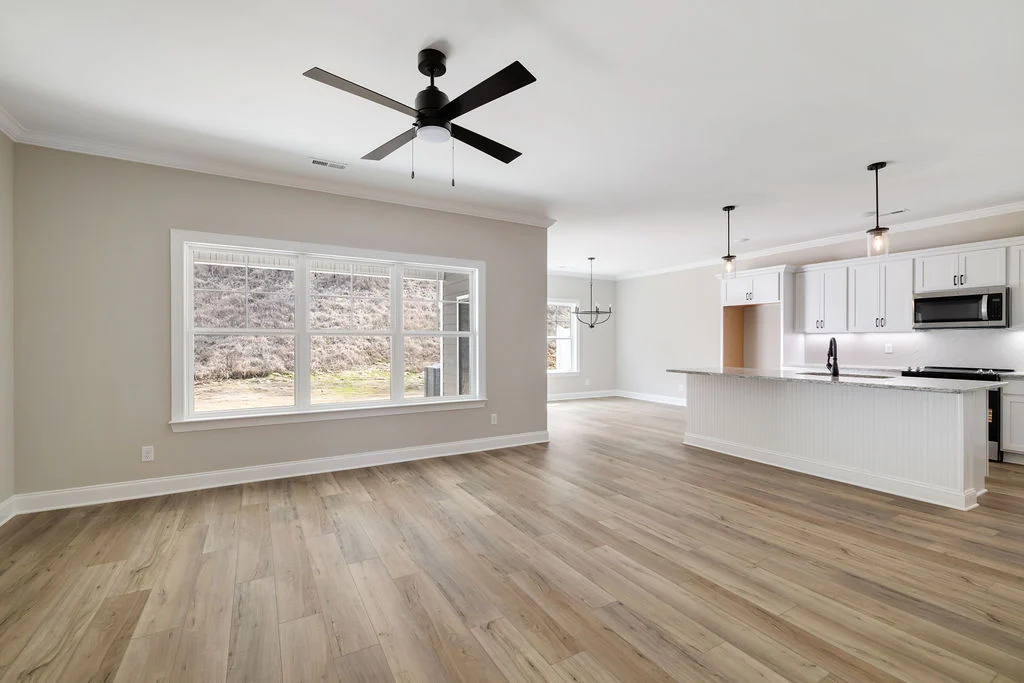 Spacious open-concept living area with hardwood floors, large windows, and modern kitchen by Pratt Home Builders in Chattanooga TN.