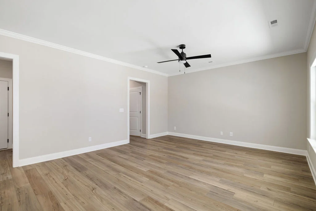 Spacious, empty room with light wood flooring, neutral walls, and ceiling fan. Constructed by Pratt Home Builders in Chattanooga TN.