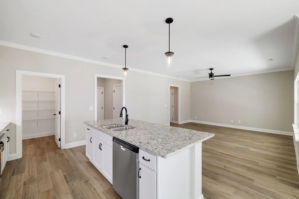 Spacious, modern kitchen and living area with granite island, hardwood floors, and neutral walls by Pratt Home Builders in Chattanooga TN.