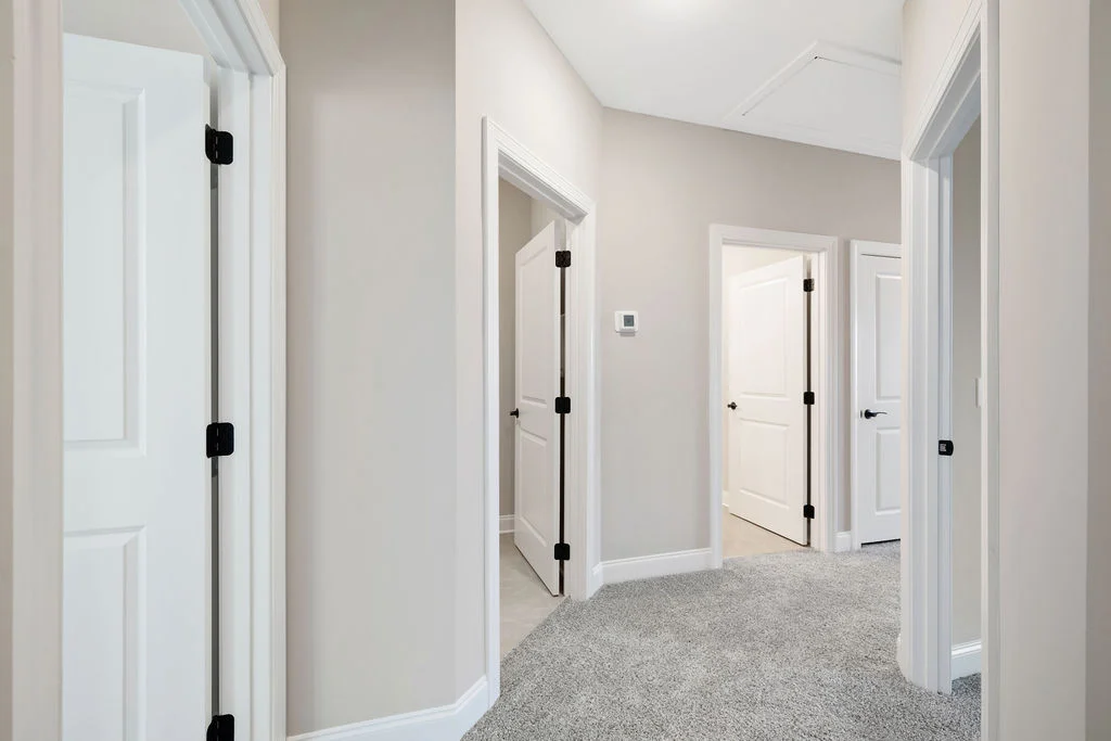Neutral-toned hallway with carpeted flooring and four panel doors, showcasing Pratt Home Builders in Chattanooga TN.