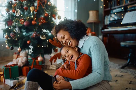 number4 Mother and child laughing by a decorated Christmas tree, surrounded by gifts, embodying warmth similar to Pratt Home Builders in Chattanooga TN.
