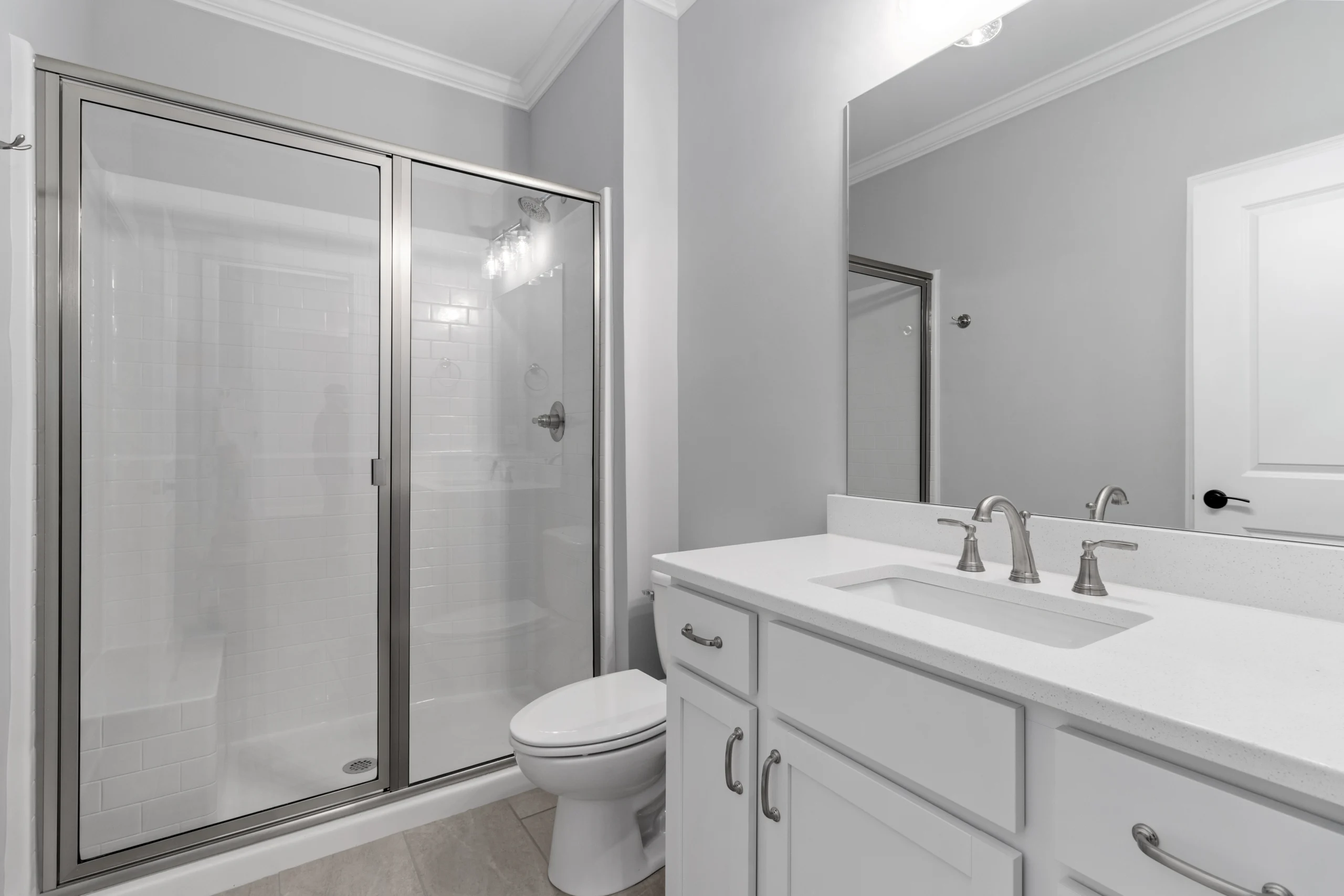 Modern bathroom with glass shower, white vanity, brushed nickel fixtures, created by Pratt Home Builders in Chattanooga TN.