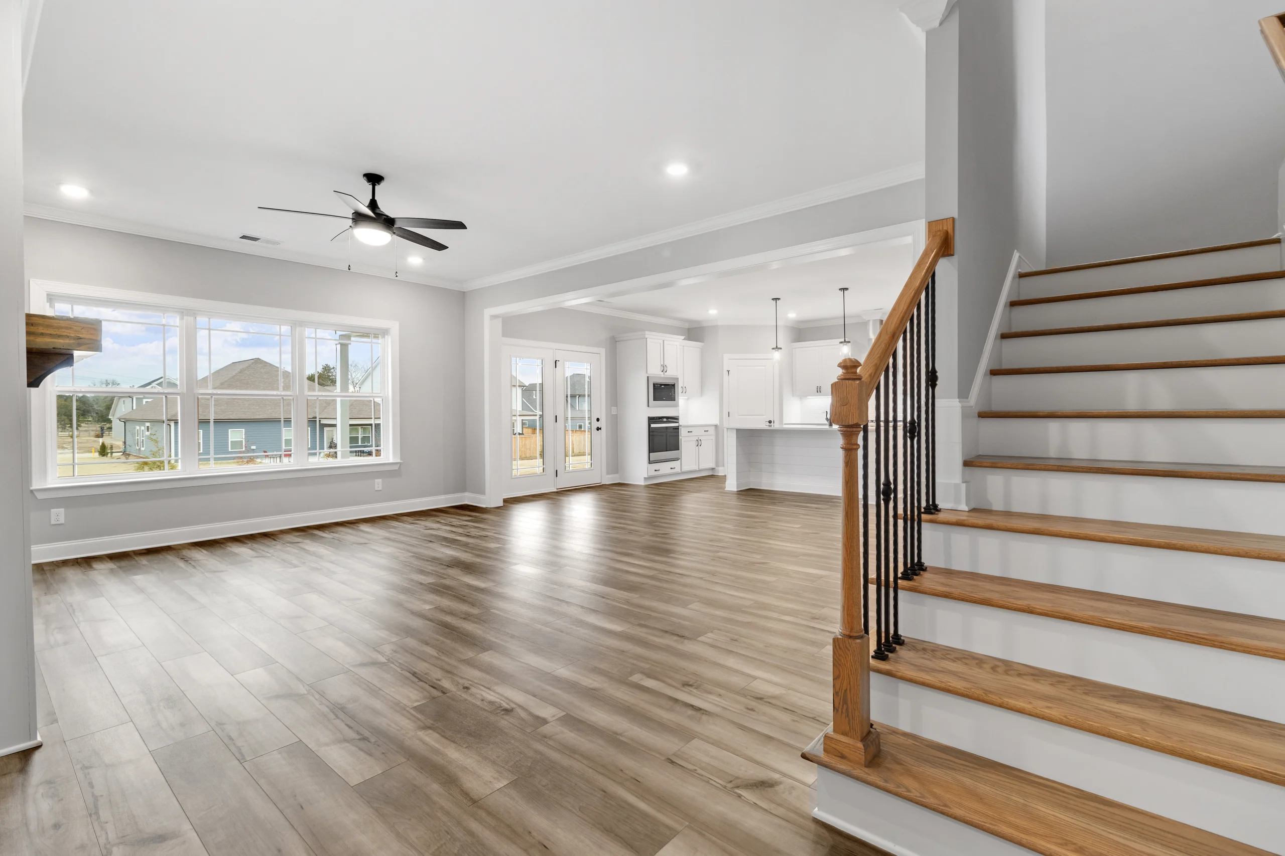 Spacious open floor plan with wooden floors, large windows, and a kitchen by Pratt Home Builders in Chattanooga, TN.