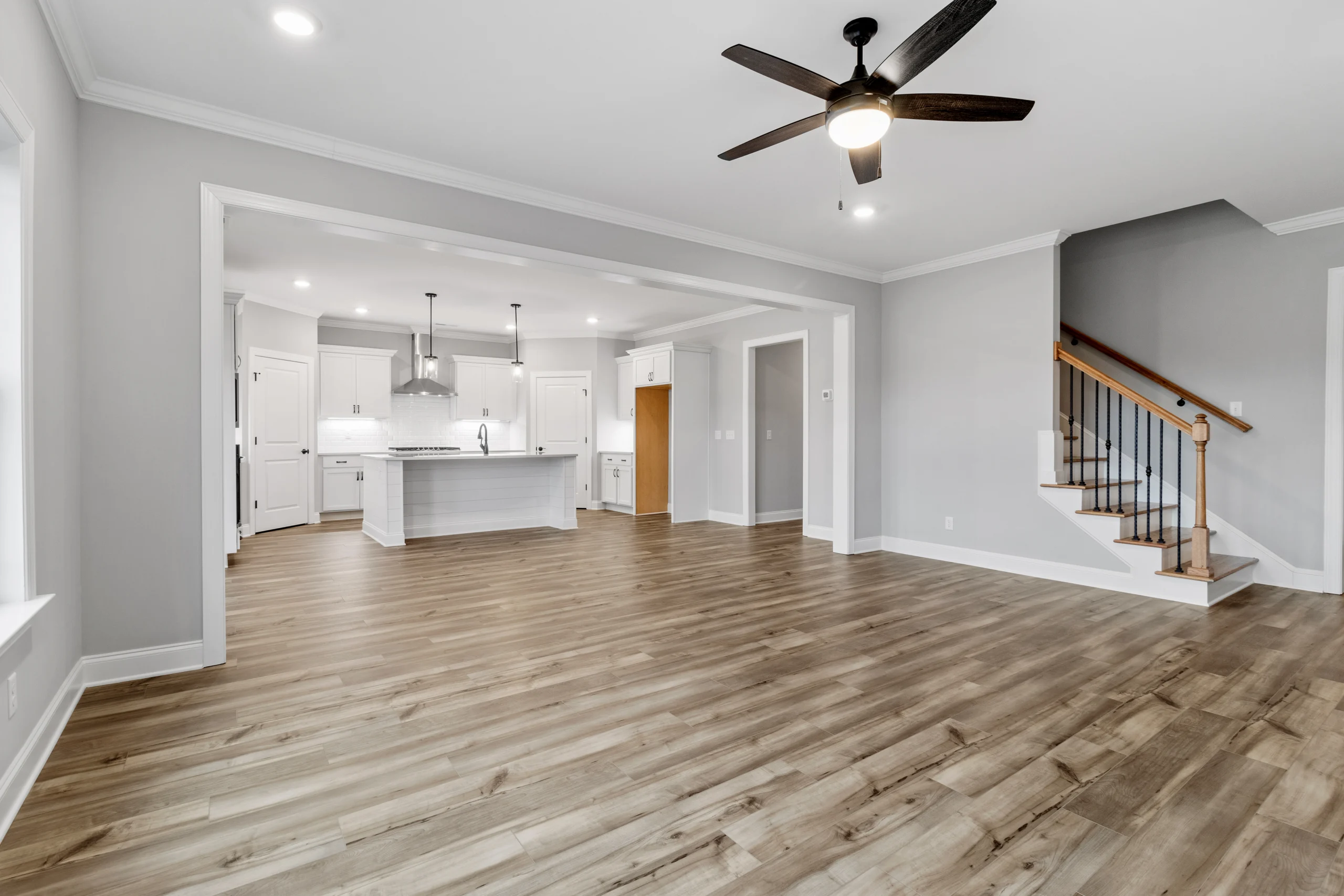 Spacious open floor plan with hardwood floors, modern kitchen, and ceiling fan by Pratt Home Builders in Chattanooga TN.