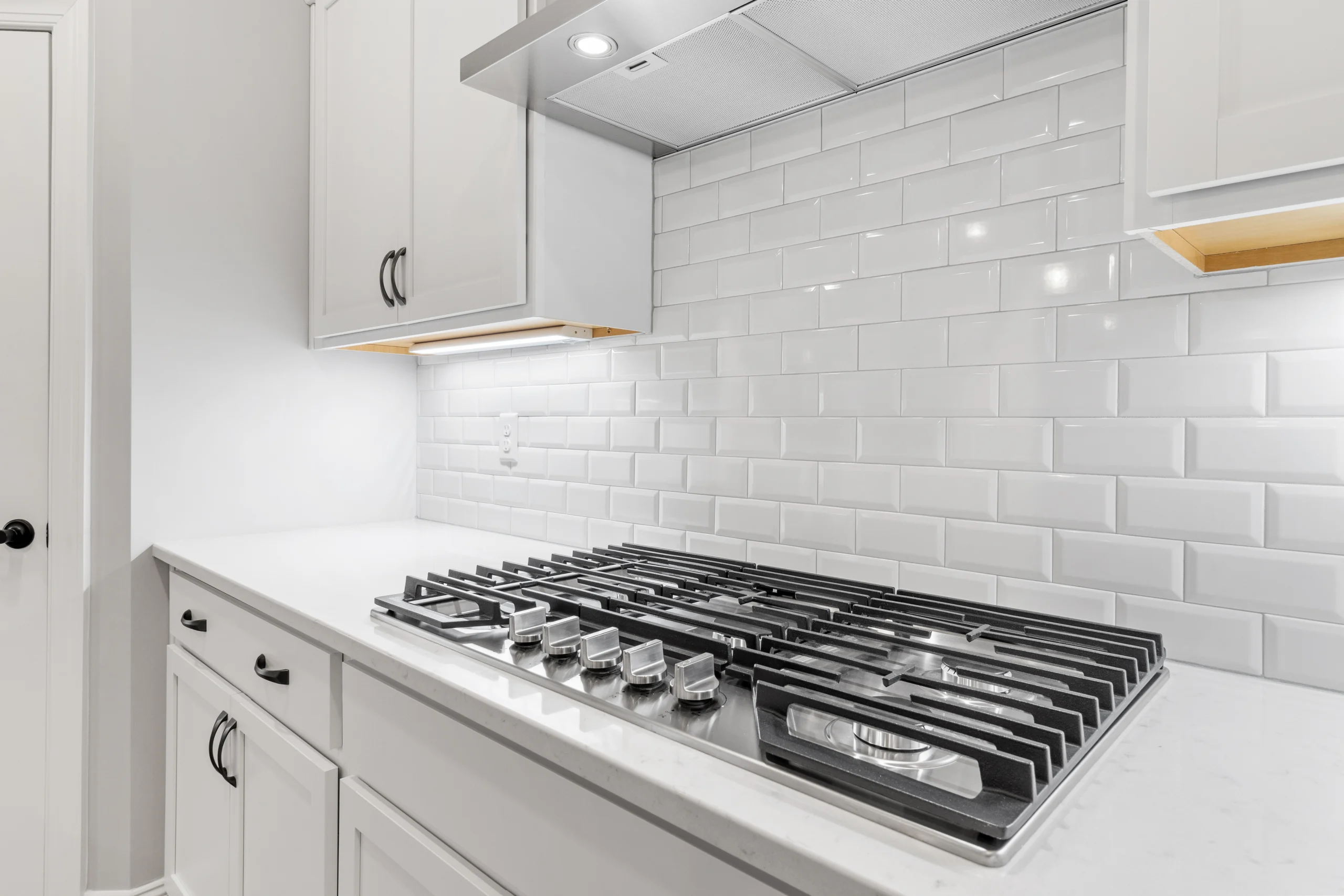 Spacious modern kitchen with stainless steel stove and white tile backsplash by Pratt Home Builders in Chattanooga TN.