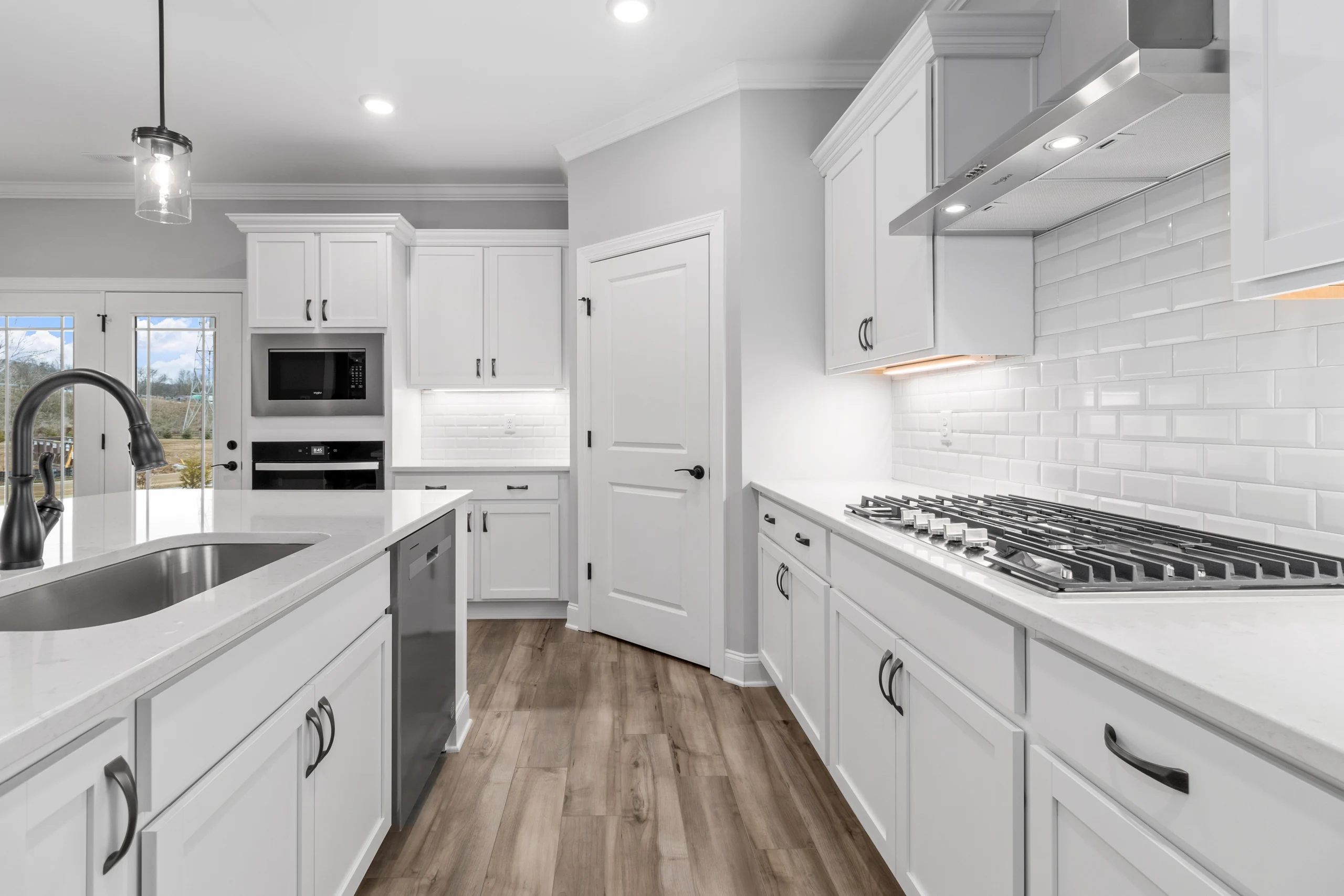 Modern kitchen by Pratt Home Builders in Chattanooga TN features white cabinets, stainless appliances, and wood flooring.