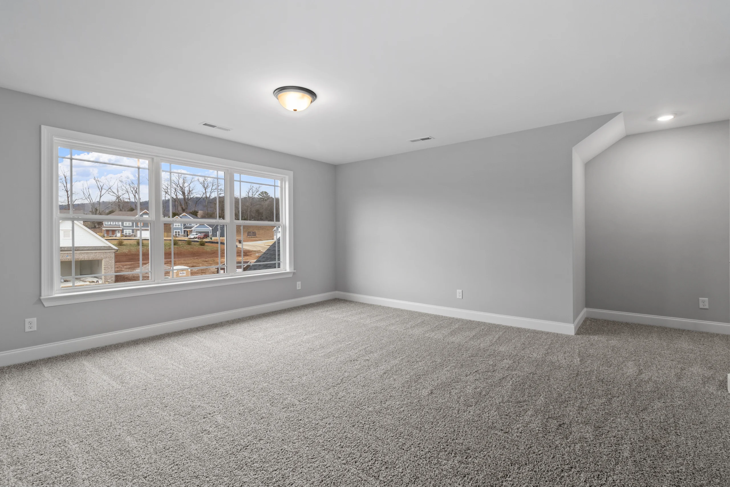 Spacious, carpeted room with large window and view of a neighborhood, built by Pratt Home Builders in Chattanooga TN.