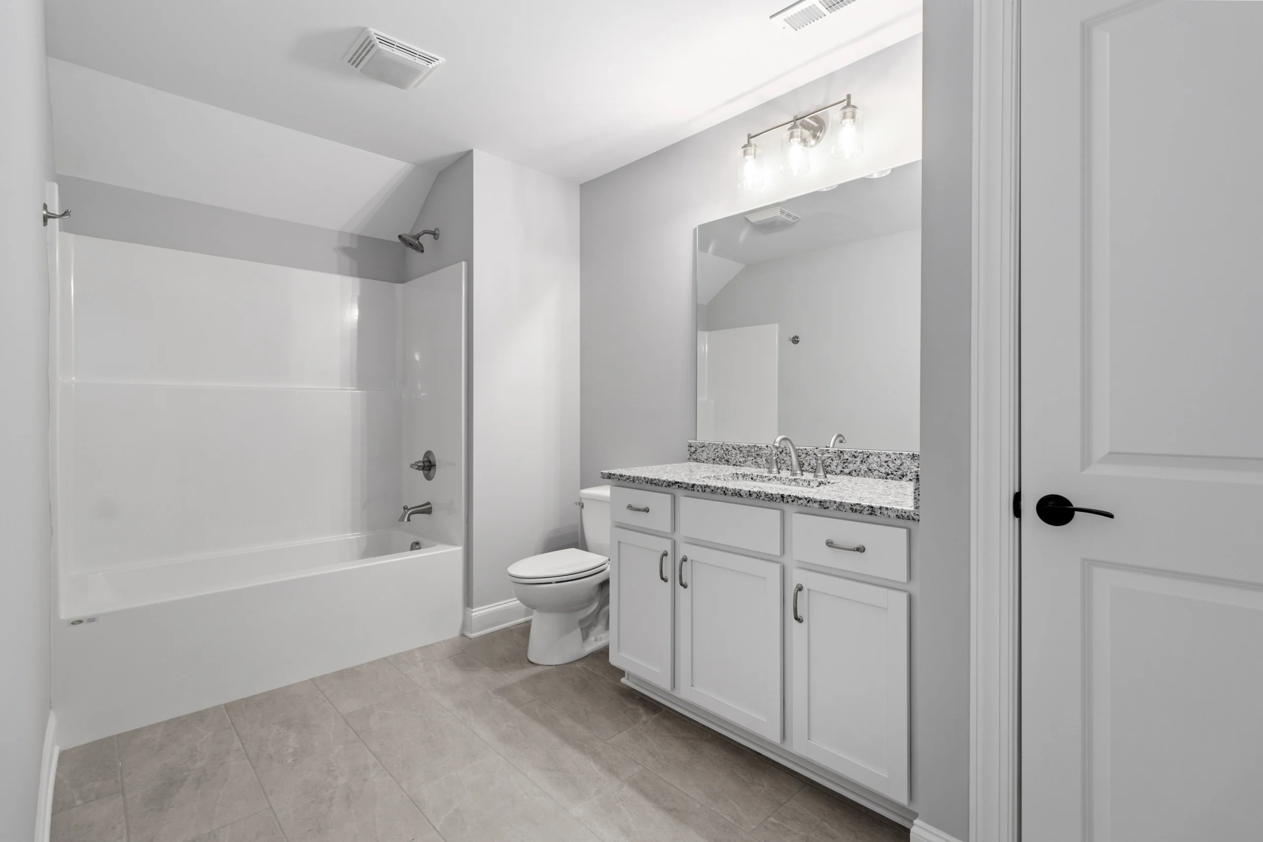 Modern bathroom with granite countertop, twin sinks, tub, and white cabinetry. Designed by Pratt Home Builders in Chattanooga TN.