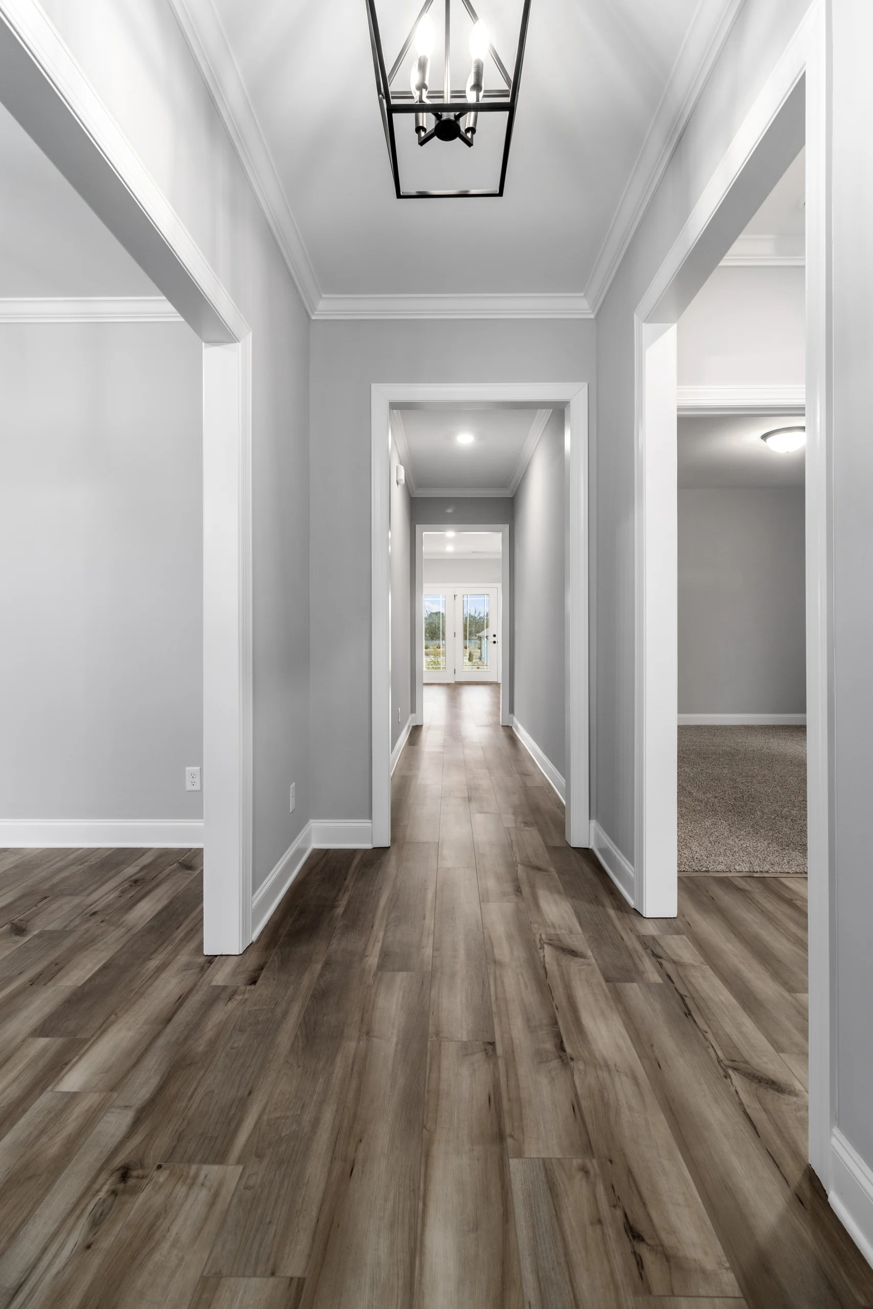 Bright hallway with wood flooring, gray walls, and modern lighting; designed by Pratt Home Builders in Chattanooga TN.