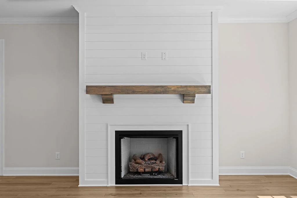 White shiplap fireplace with rustic wood mantel and brick-lined interior, designed by Pratt Home Builders in Chattanooga TN.