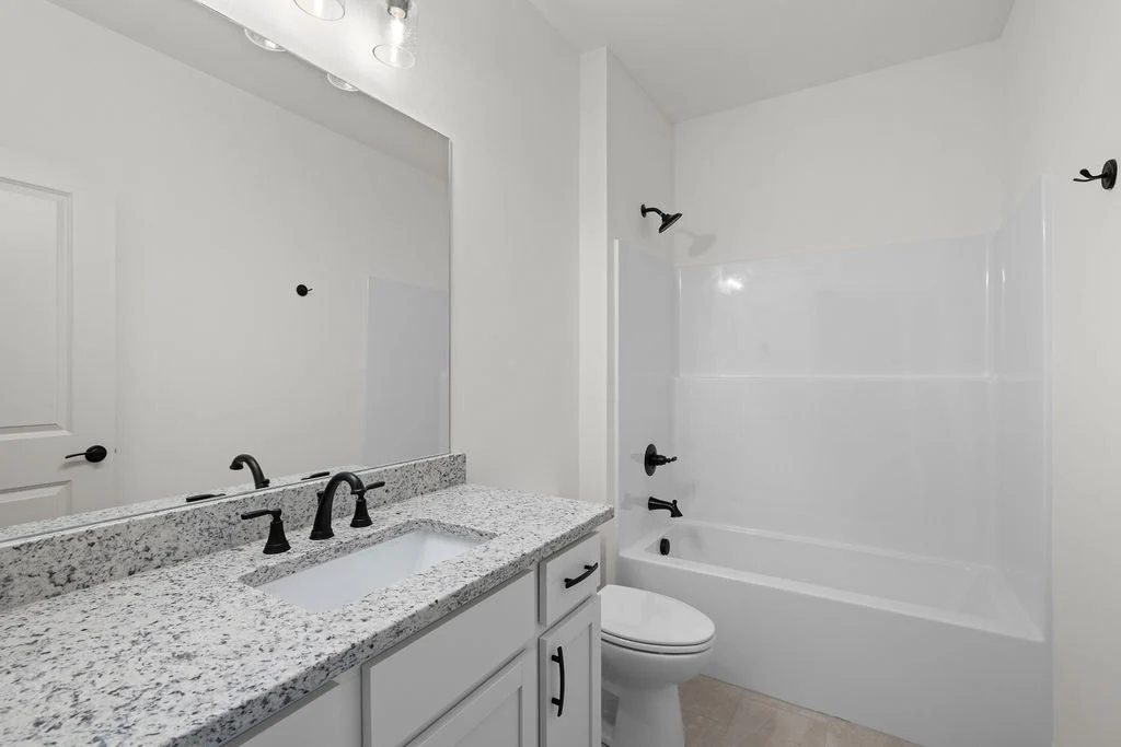 Modern bathroom with granite countertops, white cabinetry, and a bathtub by Pratt Home Builders in Chattanooga, TN.