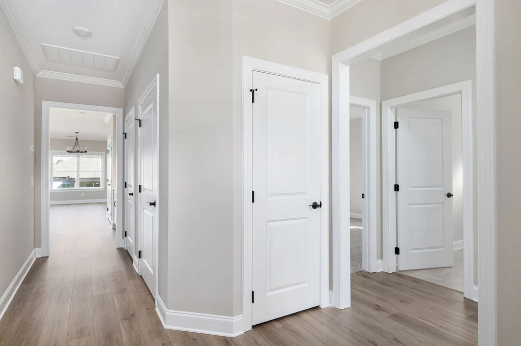 Bright hallway with hardwood floors and white doors, leading to rooms in a Pratt Home Builders property in Chattanooga, TN.