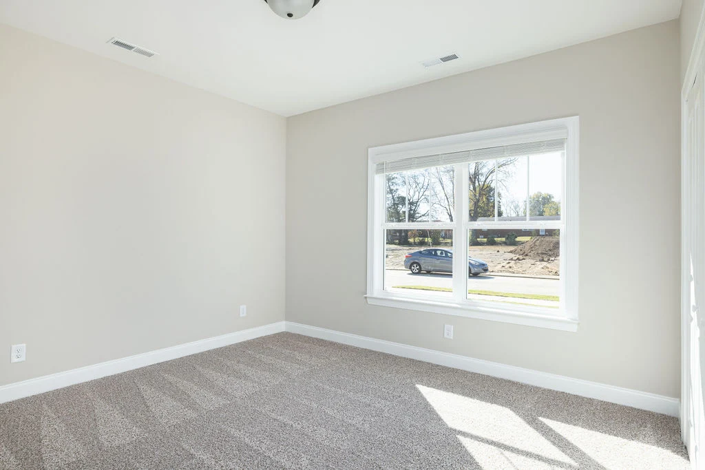 Empty beige room with large window facing the street and car outside, built by Pratt Home Builders in Chattanooga TN.