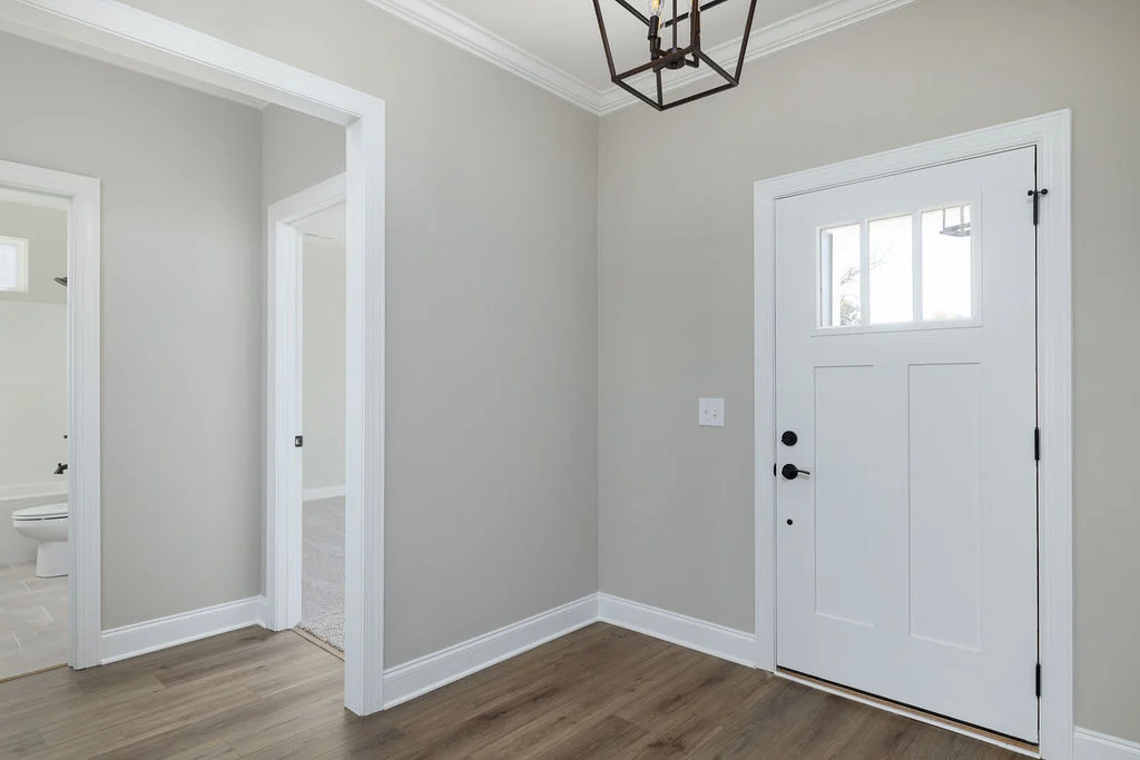 Modern entryway with white door, gray walls, hardwood floor, and minimalist light fixture by Pratt Home Builders in Chattanooga TN.