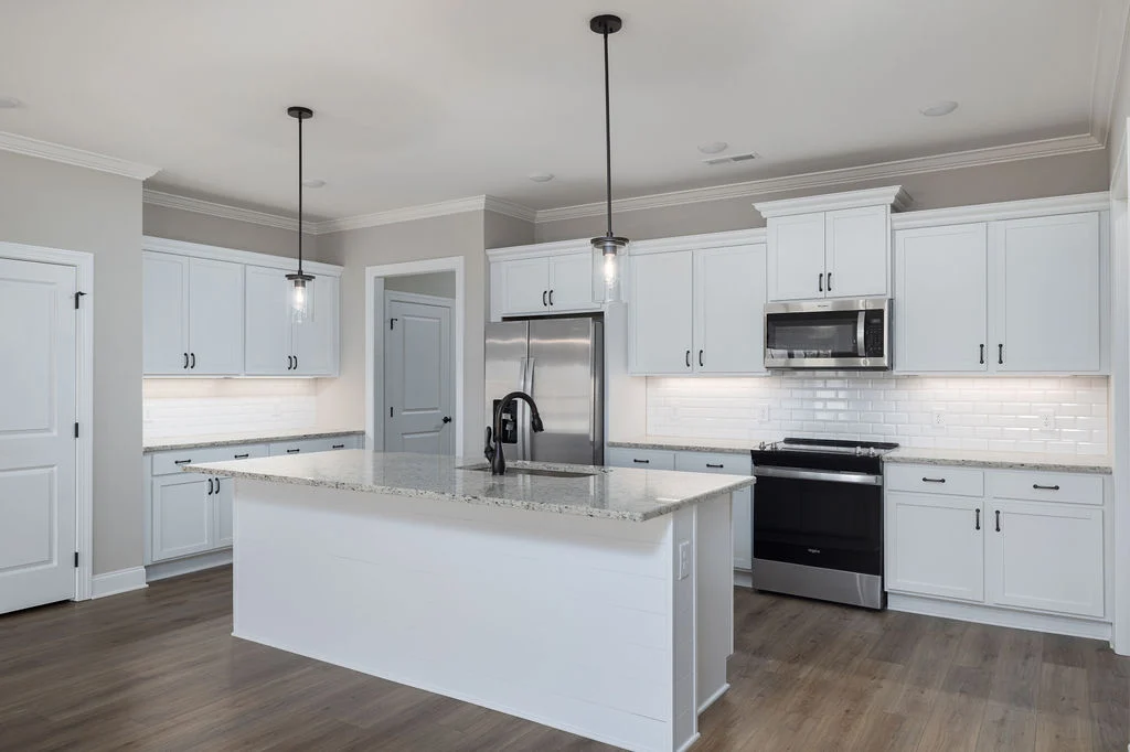 Modern kitchen with white cabinetry, granite island, stainless steel appliances, subway tile backsplash, pendant lighting. Pratt Home Builders, Chatta
