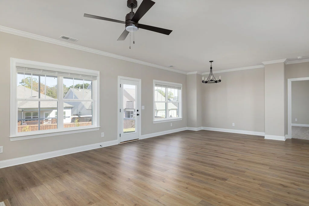 Bright, spacious living room with wood floors, large windows, ceiling fan, and chandelier by Pratt Home Builders in Chattanooga TN.